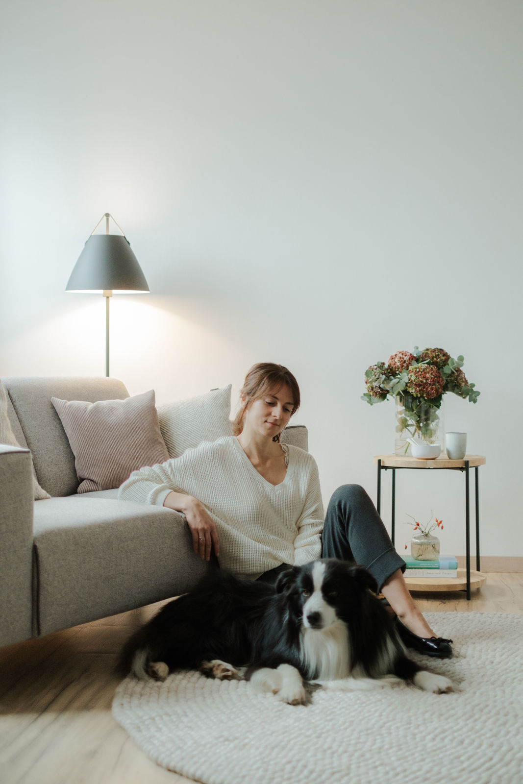 Nadine Schlesinger sitzt mit einem Hund vor einem Sofa in der Praxis